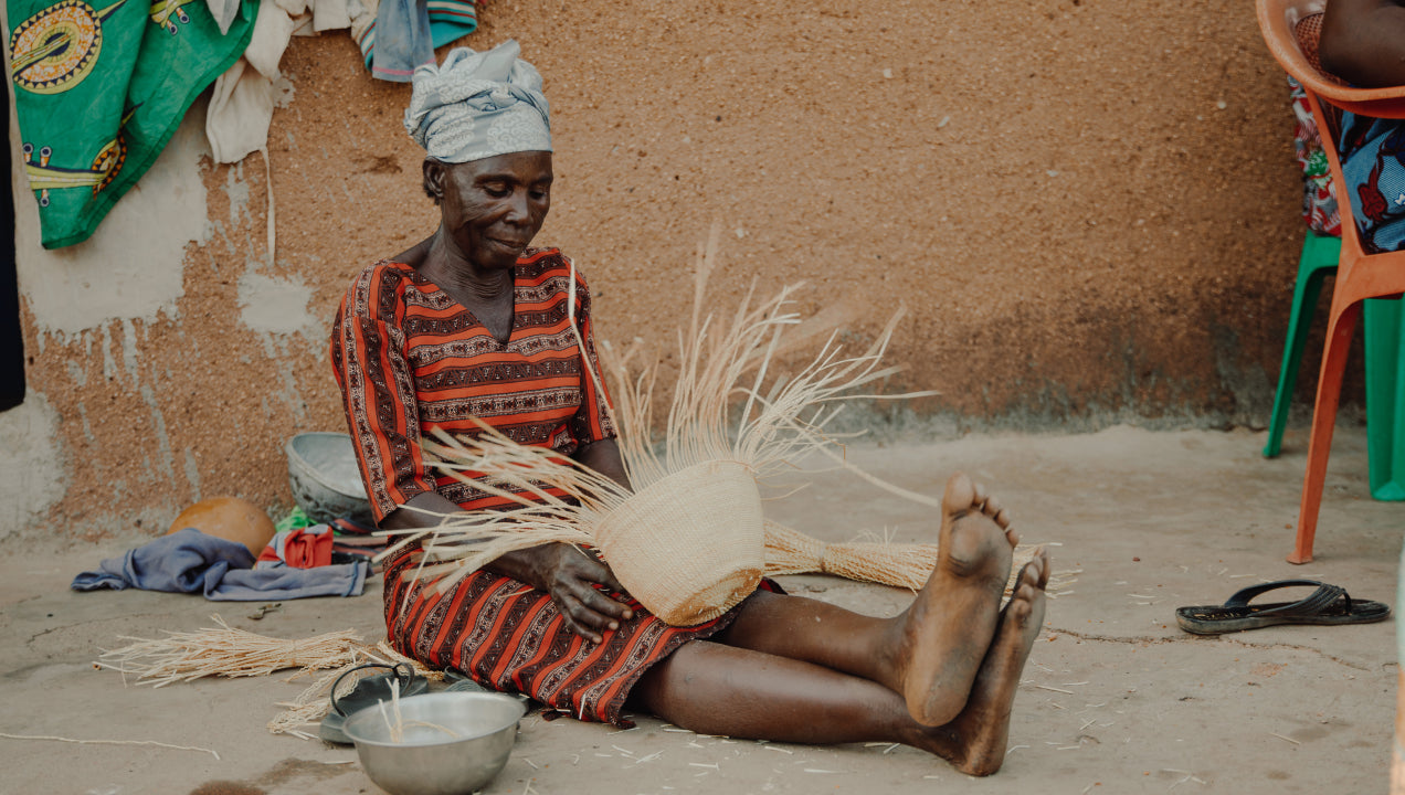 a woman sits on the ground and weaves a Frafra basket from Veta Vera Grass