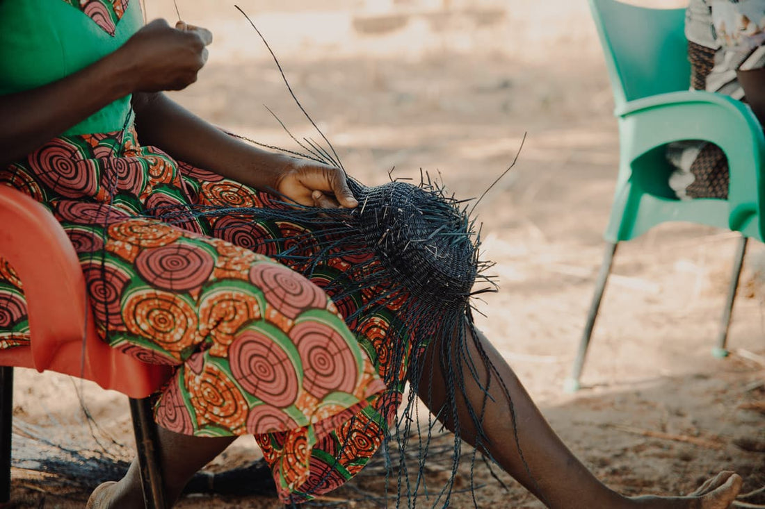 woman from Ghana sitting outside and weaves Frafra basket